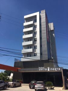 um edifício alto com carros estacionados em frente em Hotel Serra Negra em Betim