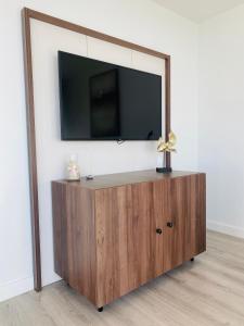 a flat screen tv on top of a wooden cabinet at Wave - Endless Sea View Apartment in Międzyzdroje