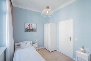 a bedroom with blue walls and a bed and a chandelier at Villa Baltik in Binz