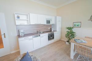 a kitchen with white cabinets and a sink and a table at Villa Baltik in Binz