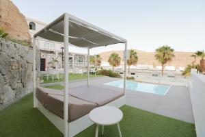 a bed with a canopy next to a swimming pool at Relaxing Apartment with Ocean Views in Puerto Rico de Gran Canaria