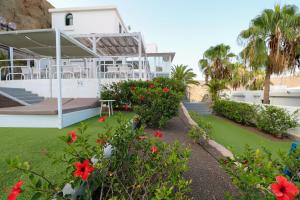 a house with a garden with red flowers at Relaxing Apartment with Ocean Views in Puerto Rico de Gran Canaria