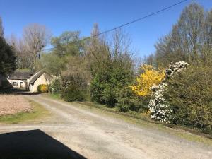 a dirt road with a house and flowers on it at Le Moulin de Crampaux in Mansigné