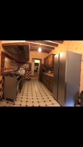 a kitchen with a refrigerator and a tiled floor at Le Moulin de Crampaux in Mansigné