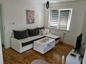 a living room with a white couch and a table at Apartman CRYSTAL in Brčko