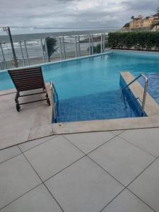 a swimming pool with a bench next to the ocean at Lindo Apartamento na Praia do Sonho in Itanhaém