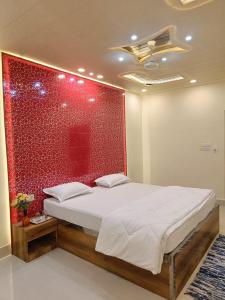 Cama en habitación con pared roja en The Royal Sahdeo Venue, en Gaya