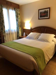 a bedroom with a large bed with a green blanket at Hotel Soldeu Maistre in Soldeu