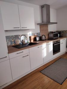 cocina blanca con armarios blancos y alfombra en Confortable appartement au centre de Sélestat, en Sélestat 12 fotos más