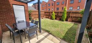 a patio with a table and chairs and a yard at Spacious House Close to Royal Derby Hospital, Free Parking & Garden in Derby