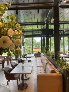 ein Restaurant mit Tischen, Sofas und Pflanzen in der Unterkunft Santa Villa & restaurant in Sremska Mitrovica