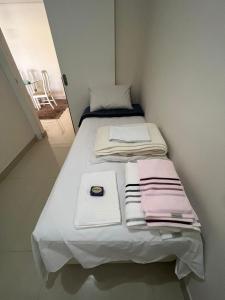 a small bed in a small room with towels on it at Flat Barra - Liberty Place in Rio de Janeiro