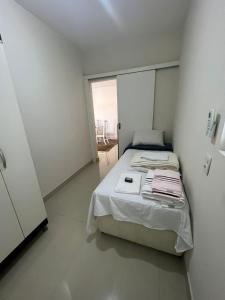 a small white bedroom with a bed and a window at Flat Barra - Liberty Place in Rio de Janeiro