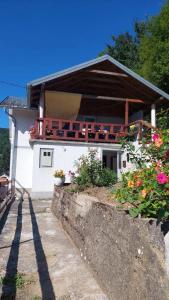 a white house with a balcony with flowers on it at Apartman Mely in Kulen Vakuf