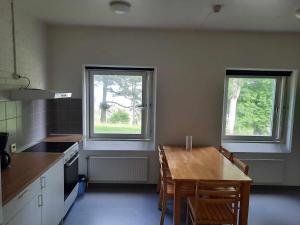 a kitchen with a wooden table and two windows at Mäshult Kurs & Lägergård in Skällinge