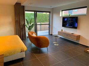 una camera con letto, TV e sedia di Q Guesthouse a Herzele