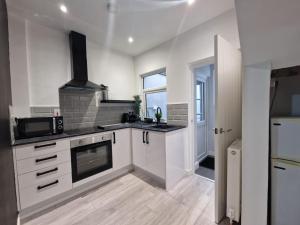 a kitchen with white cabinets and a stove top oven at Modern Belfast City Home in Belfast