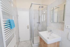 a white bathroom with a sink and a shower at Villa Baltik in Binz