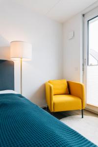 ein Schlafzimmer mit einem gelben Stuhl und einem Bett in der Unterkunft Modernes City-Appartement in Bielefeld
