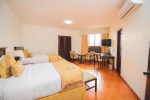 Cette chambre d'hôtel comprend deux lits, une table et des chaises. dans l'établissement Hotel Los Portales, à Chinandega