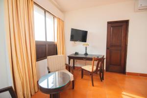 Zimmer mit einem Schreibtisch, einem Tisch und einem Fenster in der Unterkunft Hotel Los Portales in Chinandega