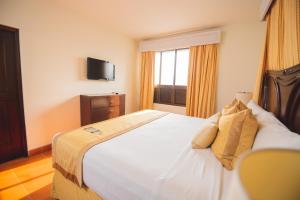 sypialnia z dużym białym łóżkiem i oknem w obiekcie Hotel Los Portales w mieście Chinandega