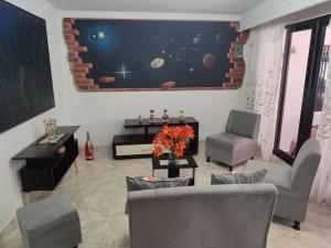 una sala de estar con sillones y una pared con un mural espacial en Apartamento en Ibague en Ibagué