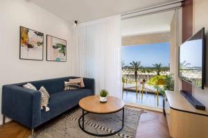 lasuita- exclusive suites cesarea- sea view suite في قيسارية: غرفة معيشة مع أريكة زرقاء وطاولة