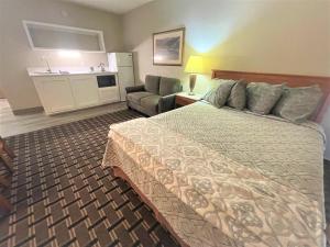 Habitación de hotel con cama y silla en FairBridge Extended Stay, a Kitchenette Hotel en Idaho Falls