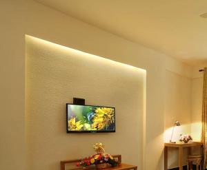 telewizor z płaskim ekranem na ścianie pokoju w obiekcie Peppervine Hotel w mieście Thekkady