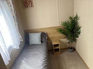 a bed in a room with a potted plant at Forest beach Shorefield Park in Lymington