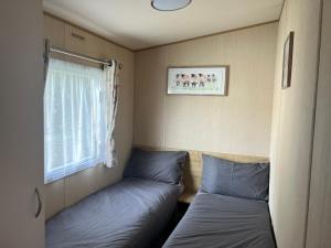 2 camas en una habitación pequeña con ventana en Forest beach Shorefield Park, en Lymington