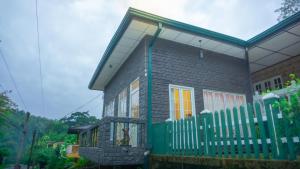 una casa con una valla verde delante de ella en Kothmale Homestay, en Mawatura