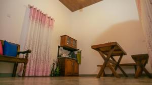 a living room with pink curtains and a wooden table at Kothmale Homestay in Mawatura