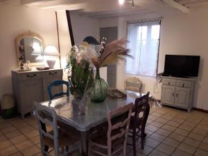 a dining room table with a vase of flowers on it at Maison chaleureuse avec cheminée des coudrais 