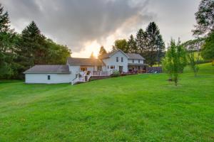 a white house on a large grassy field at Coudersport Home with Outdoor Spa and Stargazing! in Coudersport