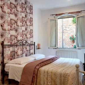 Un dormitorio con una cama y una pared cubierta de cuadros. en il vicolo delle scuole pie, en Città della Pieve