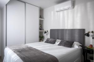 1 dormitorio con 1 cama blanca grande con almohadas negras en Athinais Grey, en Heraclión