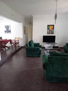uma sala de estar com sofás verdes e uma televisão em Evarist Mianzini House em Arusha