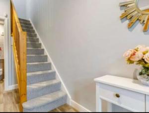 a stairway with a white staircase with a vase of flowers at The Old Warehouse. Warehouse Conversion in quiet central location 2 bed. in Great Yarmouth
