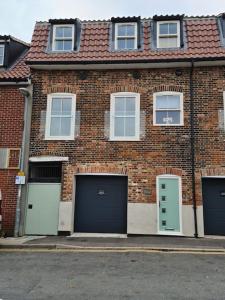 un edificio de ladrillo con dos garajes y dos puertas de garaje en The Old Warehouse. Warehouse Conversion in quiet central location 2 bed. en Great Yarmouth