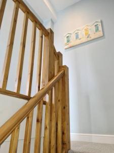 eine Holztreppe in einem Haus mit einem Gemälde an der Wand in der Unterkunft The Old Warehouse. Warehouse Conversion in quiet central location 2 bed. in Great Yarmouth