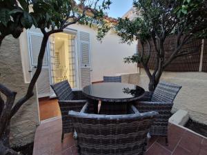 un patio con mesa, sillas y árboles en La Maddalena Holiday Home, en La Maddalena