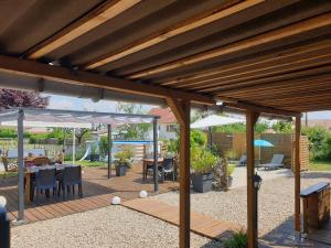 un patio de madera con mesas, sillas y sombrillas en Le Heron Pourpre B&B gastronomique, en Cronat