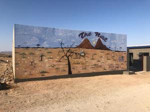 a mural on the side of a building in the desert at The Nest Overnight and Accommodation Usakos in Usakos