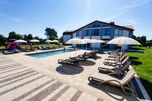 a group of lounge chairs and umbrellas next to a pool at Підгорецький маєток - готель in Pidhirtsi