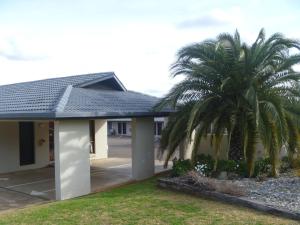 a house with two palm trees in front of it at Stagecoach Inn Motel in Tamworth