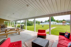 a covered patio with red furniture and a table at Charming Cadillac Retreat with Private Hot Tub! in Cadillac