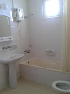 a bathroom with a sink and a toilet and a bath tub at Orange Grove Apart Hotel in Alanya