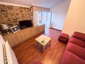 ein Wohnzimmer mit einem Sofa, einem TV und einem Tisch in der Unterkunft Casa Gonzalo in Arou
